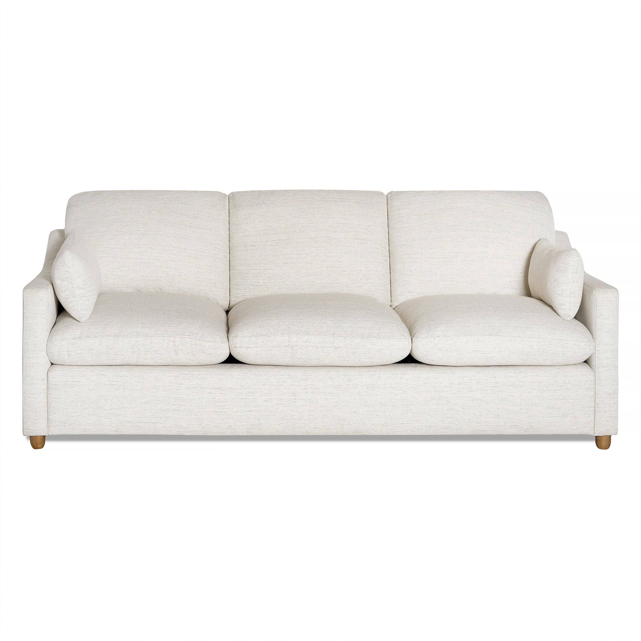 The My Cloud Slope Sofa is a minimalist white piece with three seat and back cushions. Its design includes short wooden legs, two bolster pillows, and machine-washable covers for easy maintenance.
