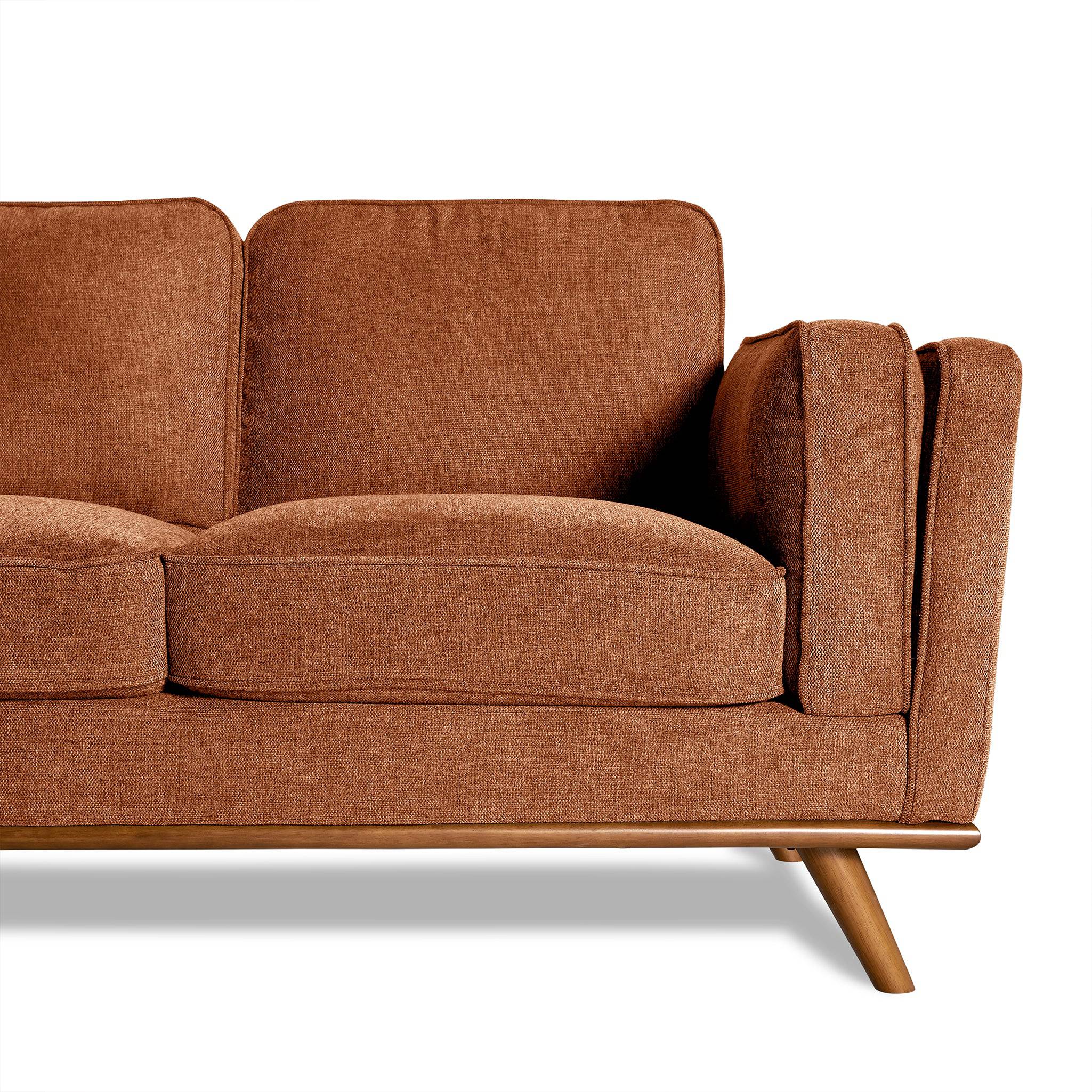 The Maddox Sectional, with its mid-century modern style, features brown upholstery, cushioned seats, angled wooden legs, and a right-side armrest. These elements elevate any living room space. The image highlights the elegant sofas right half.