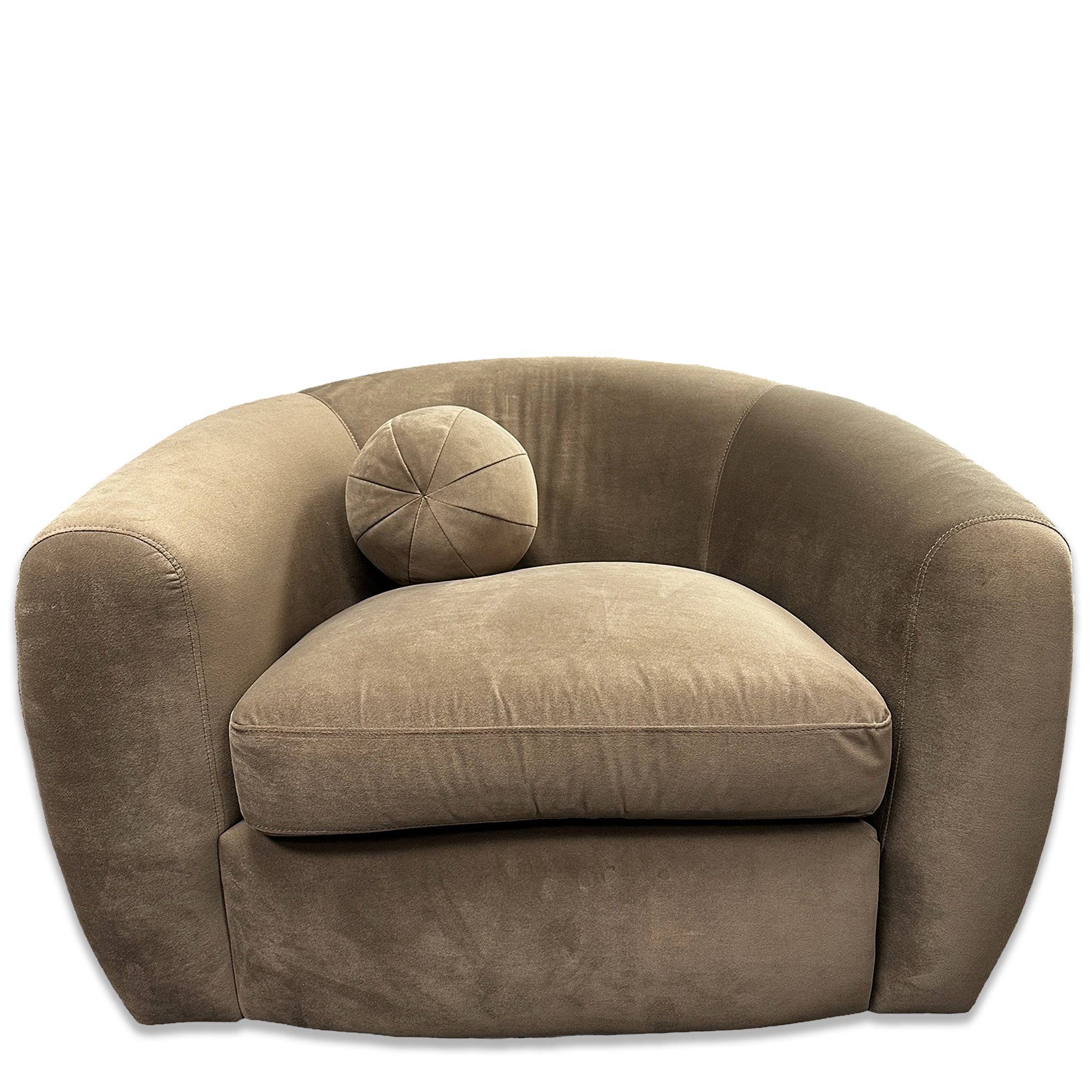 The Sculpture Swivel Chair is a large plush beige armchair with a rounded back and wide arms, featuring luxurious velvety-soft upholstery and a single round cushion on the seat for maximum comfort.