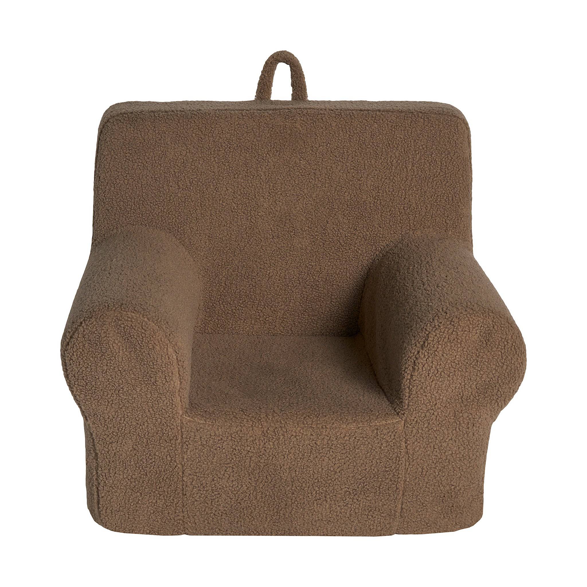 Meet the My Cloud Kidz Chair, a cozy brown childrens armchair made of plush Sherpa fabric. It features rounded armrests, a backrest, and a small loop handle on top for easy carrying, offering comfort and practicality in one design.